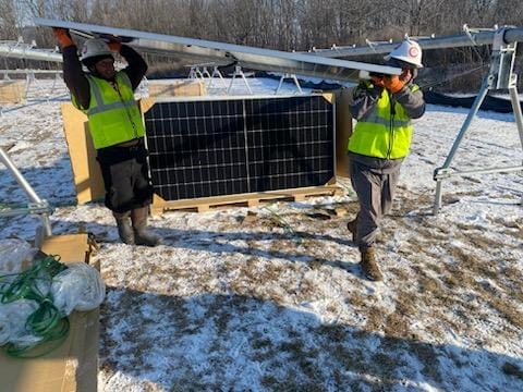 Construction workers carry a solar panel during installation
